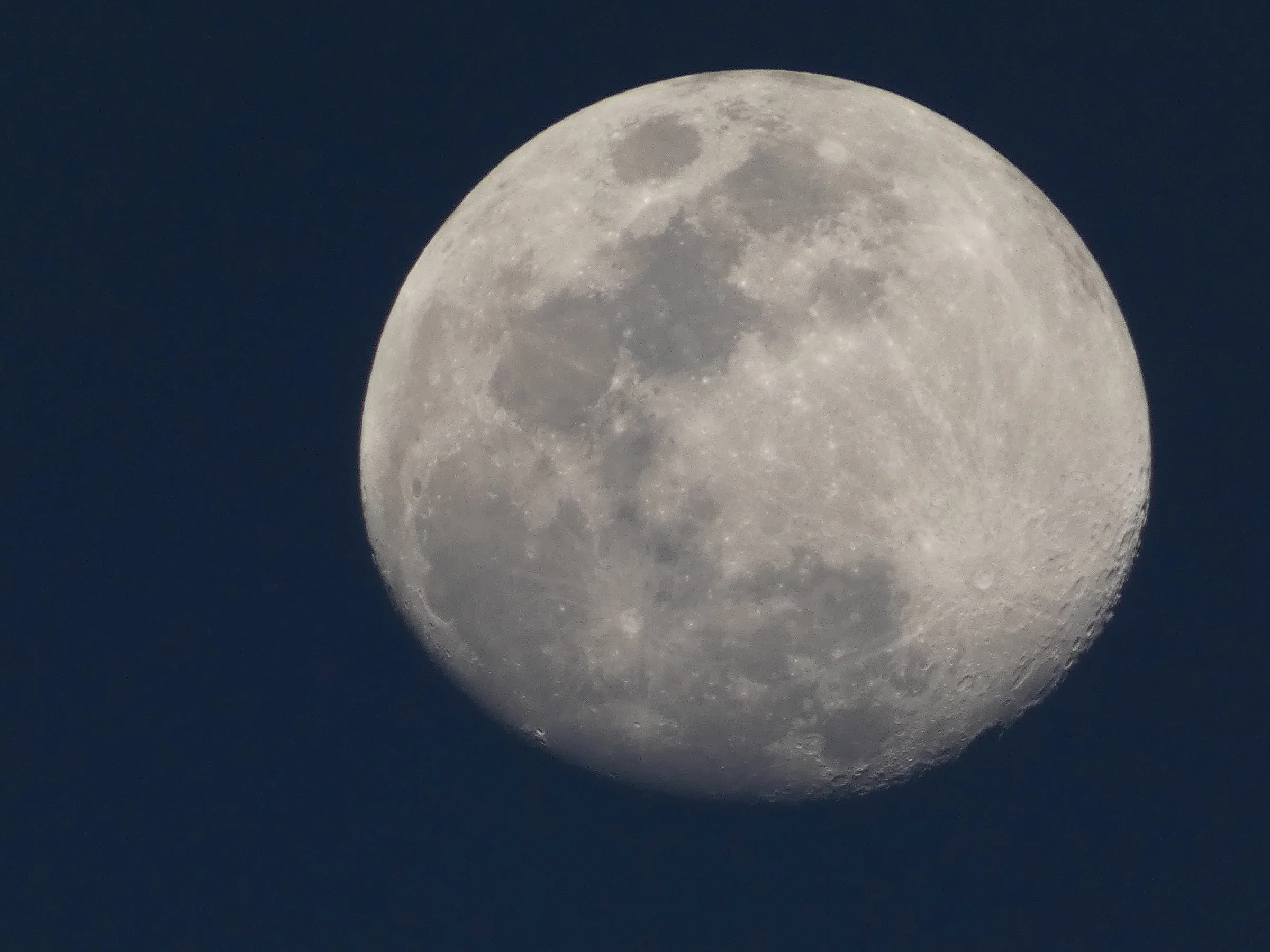 Lua quase cheia com crateras e texturas visíveis contra o céu escuro.